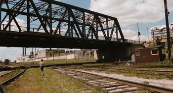 Movie still from “The Black Stallion” (1979), directed by Carroll Ballard – A man walking across a train track next to train tracks; Extreme Wide shot, High angle