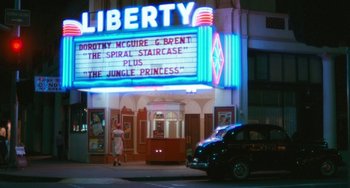 Movie still from “The Black Stallion” (1979), directed by Carroll Ballard – A car parked in front of a lit up theater; Extreme Wide shot, Low angle