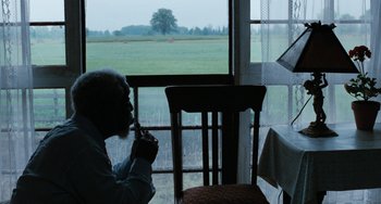 Movie still from “The Black Stallion” (1979), directed by Carroll Ballard – An older man sitting at a table in front of a window; Wide shot, Over the shoulder angle