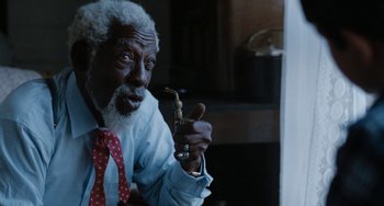 Movie still from “The Black Stallion” (1979), directed by Carroll Ballard – An older man holding a pipe in his mouth; Close Up shot, Low angle