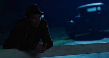 Movie still from “The Black Stallion” (1979), directed by Carroll Ballard – An older man in a hat is leaning against a wall; Medium shot, Over the shoulder angle