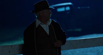 Movie still from “The Black Stallion” (1979), directed by Carroll Ballard – An older man wearing a hat standing next to a fence; Medium shot, Over the shoulder angle