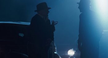 Movie still from “The Black Stallion” (1979), directed by Carroll Ballard – A man in a hat is holding a pair of scissors in his hand; Medium shot, Over the shoulder angle
