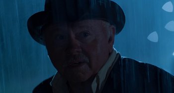 Movie still from “The Black Stallion” (1979), directed by Carroll Ballard – An older man wearing a hat in the rain; Close Up shot, Low angle