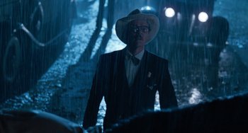Movie still from “The Black Stallion” (1979), directed by Carroll Ballard – A man in a suit and hat standing in the rain at night; Medium shot, Over the shoulder angle