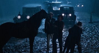 Movie still from “The Black Stallion” (1979), directed by Carroll Ballard – A group of men standing next to a horse in the rain; Wide shot, Over the shoulder angle