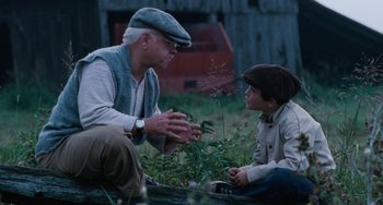Movie still from “The Black Stallion” (1979), directed by Carroll Ballard – An older man and a young boy sitting on the ground; Medium shot, Over the shoulder angle