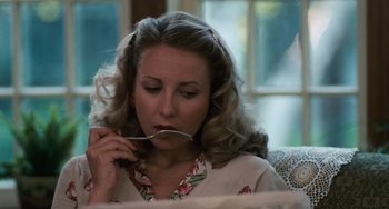 Movie still from “The Black Stallion” (1979), directed by Carroll Ballard – A woman sitting on a couch holding a spoon in her mouth; Close Up shot, High angle