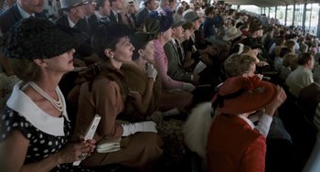 Movie still from “The Black Stallion” (1979), directed by Carroll Ballard – A group of people sitting in a crowd wearing hats and gloves; Medium shot, High angle