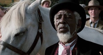 Movie still from “The Black Stallion” (1979), directed by Carroll Ballard – An old man with a beard and a hat and a white horse; Close Up shot, Low angle