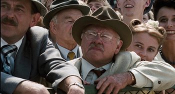 Movie still from “The Black Stallion” (1979), directed by Carroll Ballard – A man in a suit and hat hugging another man in a suit and hat; Close Up shot, Over the shoulder angle