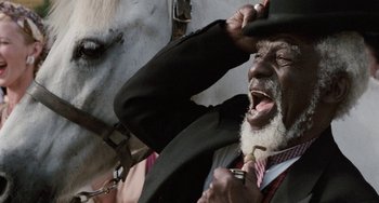 Movie still from “The Black Stallion” (1979), directed by Carroll Ballard – An older man with a beard and a hat on a horse; Close Up shot, Low angle
