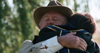 Movie still from “The Black Stallion” (1979), directed by Carroll Ballard – An older man holding a child in his arms; Close Up shot, Over the shoulder angle