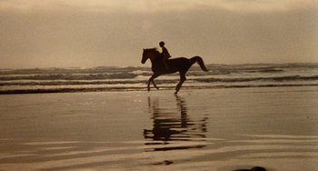 Movie still from “The Black Stallion” (1979), directed by Carroll Ballard – A person riding a horse on a beach near the ocean; Extreme Wide shot, High angle