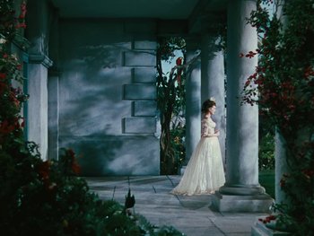 Movie still from “The Black Swan” (1942), directed by Henry King – A woman in a long white dress standing in front of pillars; Wide shot, Low angle