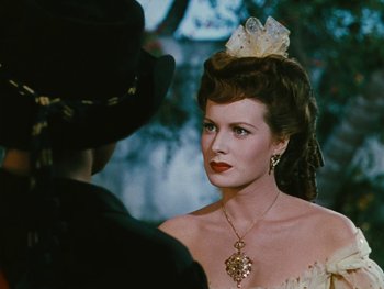 Movie still from “The Black Swan” (1942), directed by Henry King – A woman wearing a necklace and a hat; Close Up shot, Over the shoulder angle