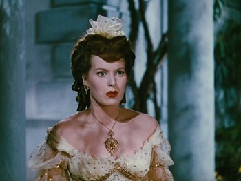 Movie still from “The Black Swan” (1942), directed by Henry King – A woman in a white dress with a flower in her hair; Close Up shot, Over the shoulder angle