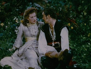 Movie still from “The Black Swan” (1942), directed by Henry King – A man and a woman sitting on the ground; Medium shot, High angle