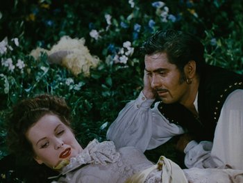 Movie still from “The Black Swan” (1942), directed by Henry King – A man and a woman sitting on the ground; Medium shot, High angle