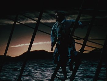 Movie still from “The Black Swan” (1942), directed by Henry King – A man standing on top of a boat in the water; Wide shot, Low angle
