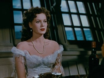 Movie still from “The Black Swan” (1942), directed by Henry King – A woman wearing a white dress and pearls; Medium shot, Over the shoulder angle
