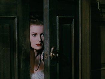Movie still from “The Black Swan” (1942), directed by Henry King – A woman with a pearl necklace peeks out from behind a door; Close Up shot, High angle