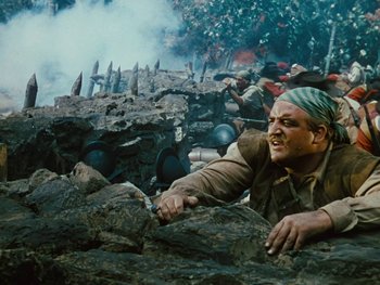 Movie still from “The Black Swan” (1942), directed by Henry King – A man with a bandana on his head is climbing a rock; Medium shot, Low angle