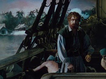 Movie still from “The Black Swan” (1942), directed by Henry King – A man with a beard is sitting on a boat; Medium shot, Over the shoulder angle