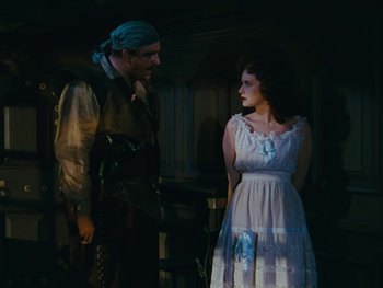 Movie still from “The Black Swan” (1942), directed by Henry King – A man and a woman standing next to each other in a dark room; Medium shot, High angle