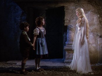 Movie still from “The Blue Bird” (1940), directed by Walter Lang – A woman in a white dress standing next to two young children; Wide shot, Low angle