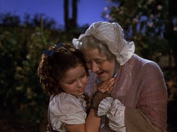 Movie still from “The Blue Bird” (1940), directed by Walter Lang – An older woman holding a young girl in her arms; Medium shot, High angle