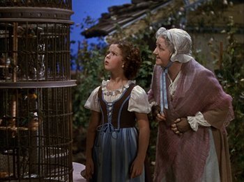 Movie still from “The Blue Bird” (1940), directed by Walter Lang – A woman standing next to a little girl in front of a bird cage; Medium shot, Low angle