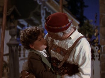 Movie still from “The Blue Bird” (1940), directed by Walter Lang – An older man and a young boy are kissing; Medium shot, Low angle