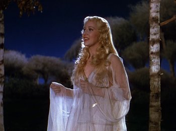 Movie still from “The Blue Bird” (1940), directed by Walter Lang – A beautiful blonde woman in a long white dress; Medium shot, Low angle