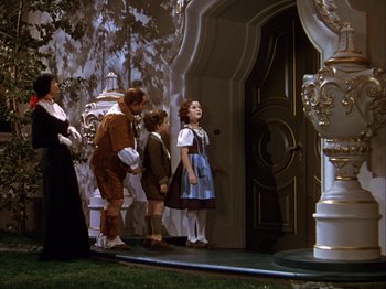 Movie still from “The Blue Bird” (1940), directed by Walter Lang – A group of people standing in front of a doorway; Wide shot, Low angle