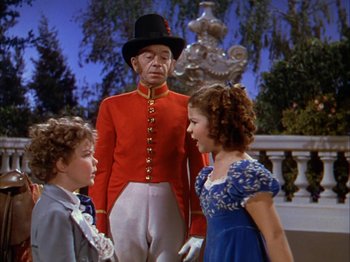 Movie still from “The Blue Bird” (1940), directed by Walter Lang – A man and two children standing next to each other in front of a fountain; Medium shot, Low angle