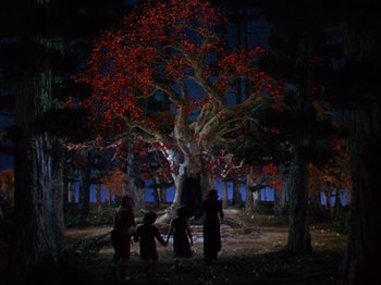 Movie still from “The Blue Bird” (1940), directed by Walter Lang – A group of people standing under a tree at night; Extreme Wide shot, Low angle