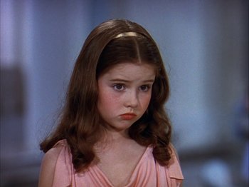Movie still from “The Blue Bird” (1940), directed by Walter Lang – A little girl in a pink dress looking sad; Close Up shot, High angle