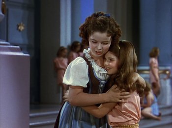 Movie still from “The Blue Bird” (1940), directed by Walter Lang – Two young girls hugging each other in front of a group of people; Medium shot, Low angle