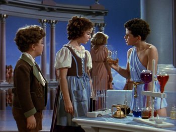 Movie still from “The Blue Bird” (1940), directed by Walter Lang – A group of people standing around a table with wine glasses on top of it; Medium shot, High angle