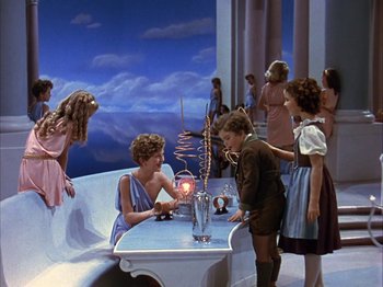 Movie still from “The Blue Bird” (1940), directed by Walter Lang – A group of people standing around a table; Wide shot, High angle