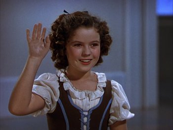 Movie still from “The Blue Bird” (1940), directed by Walter Lang – A young girl waving to the camera while wearing a dress; Medium shot, High angle