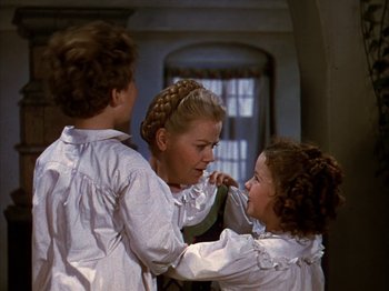Movie still from “The Blue Bird” (1940), directed by Walter Lang – A woman and two young children in white shirts; Medium shot, Over the shoulder angle