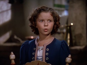 Movie still from “The Blue Bird” (1940), directed by Walter Lang – A little girl with curly brown hair is standing in front of a chair; Close Up shot, High angle