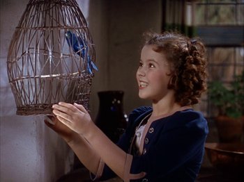 Movie still from “The Blue Bird” (1940), directed by Walter Lang – A little girl holding a bird in a bird cage; Close Up shot, High angle