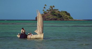 Movie still from “The Blue Lagoon” (1980), directed by Randal Kleiser – A small sail boat in the water near the shore; Extreme Wide shot, High angle