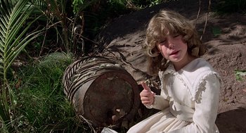Movie still from “The Blue Lagoon” (1980), directed by Randal Kleiser – A young girl sitting in front of an old rusted barrel; Close Up shot, High angle