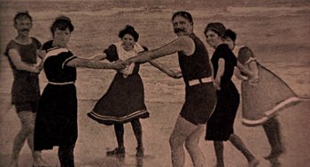 Movie still from “The Blue Lagoon” (1980), directed by Randal Kleiser – A group of people standing on top of a sandy beach; Wide shot, High angle