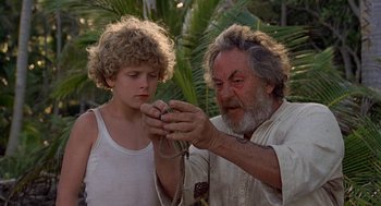 Movie still from “The Blue Lagoon” (1980), directed by Randal Kleiser – An older man and a young boy looking at a piece of rope; Close Up shot, High angle