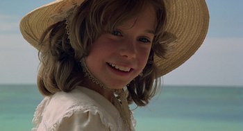 Movie still from “The Blue Lagoon” (1980), directed by Randal Kleiser – A little girl wearing a straw hat smiling for the camera; Close Up shot, High angle